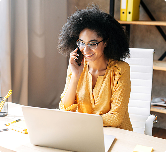 A woman on the phone using her computer