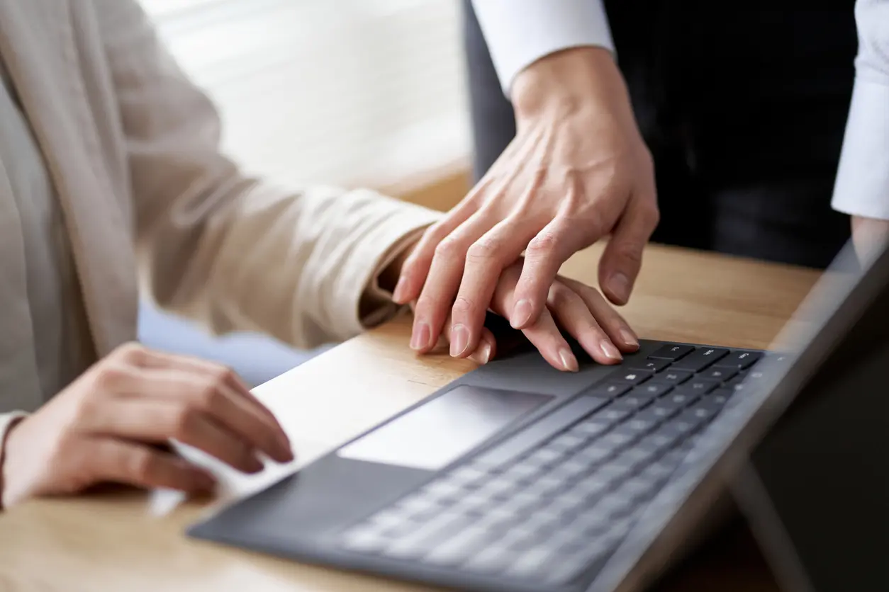 Two hands touching over a laptop