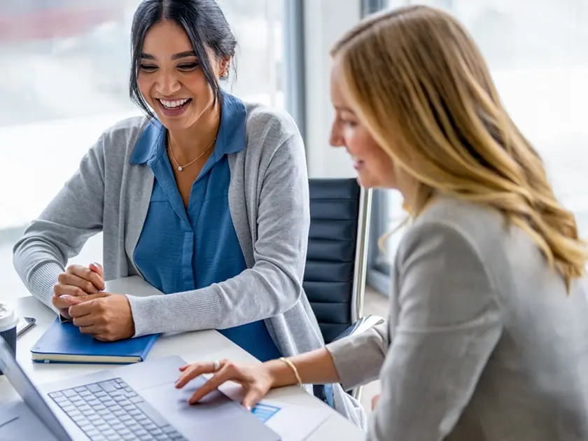 Two Women chatting at desk